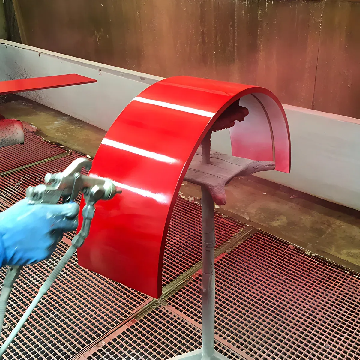 Laccatura a spruzzo di un pannello rosso nella cabina di finitura